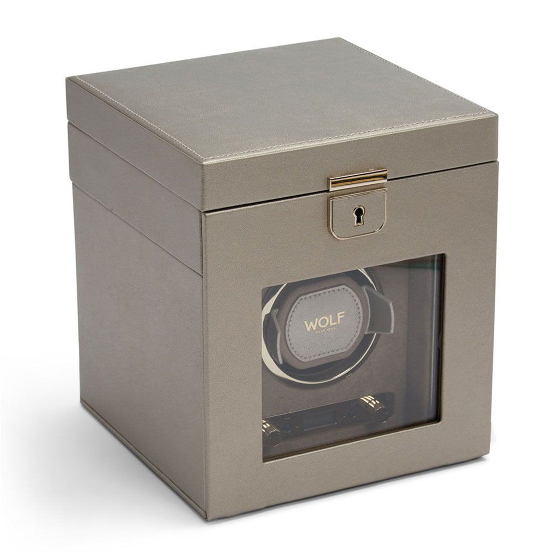 The WOLF 1834 Palermo Single Watch Winder with Jewelry Storage, in gray, elegantly showcases a watch inside its transparent front panel. This sophisticated design offers rotation options and includes a lockable latch on the top for secure winding.