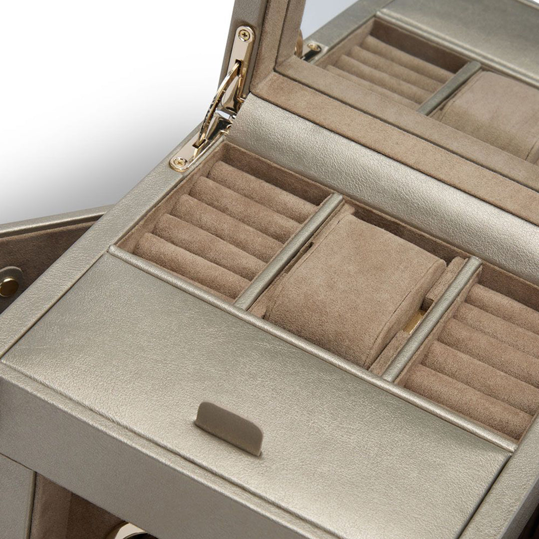 Close-up of an open WOLF 1834 Palermo Single Watch Winder with Jewelry Storage, showcasing a beige velvet-lined interior and patented innovation. The product provides multiple compartments for organizing jewelry, featuring ring slots and a watch holder with rotation options. Its metallic exterior is elegantly accented by gold hinges.