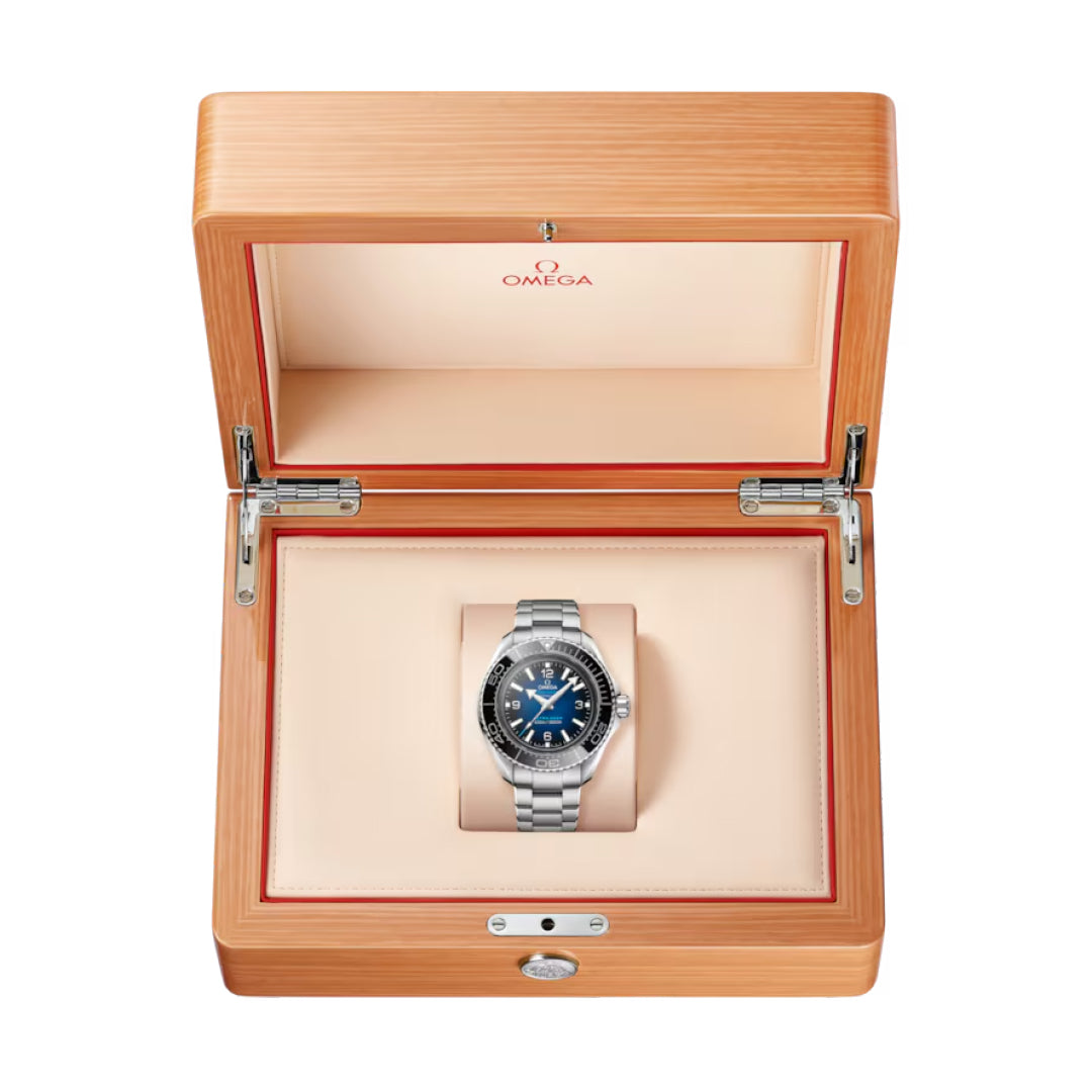 The OMEGA Seamaster Planet Ocean 6000M Ultra Deep Co-Axial Master Chronometer 45.5mm Watch is shown in an open light wood box with cream interior and OMEGA logo, highlighting its water-resistant design and striking blue face.