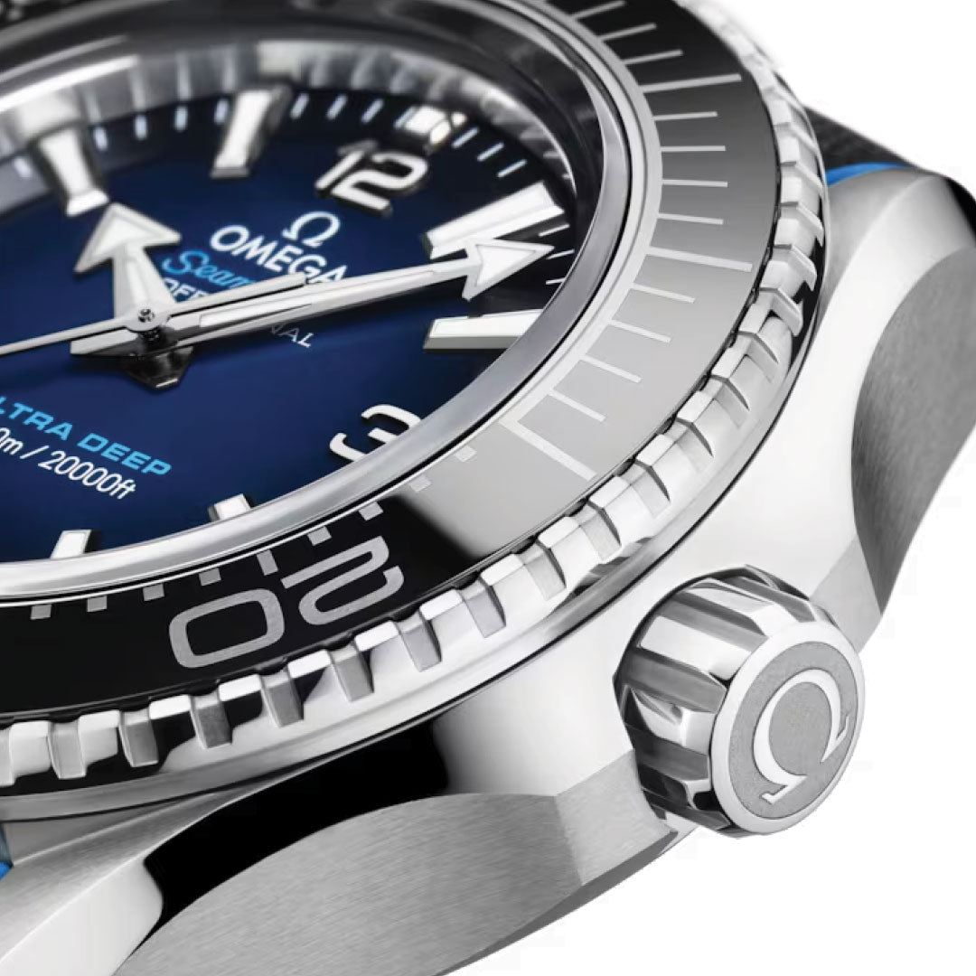 Captured in detail is the luxurious OMEGA Seamaster Planet Ocean 6000M Ultra Deep Co-Axial Master Chronometer 45.5mm Watch, featuring a striking silver bezel. Its blue dial showcases bold white hour markers and hands, highlighted by the iconic OMEGA Seahorse emblem. Proudly labeled "Ultra Deep," this remarkable timepiece boasts water resistance up to an impressive depth of 6000 meters.