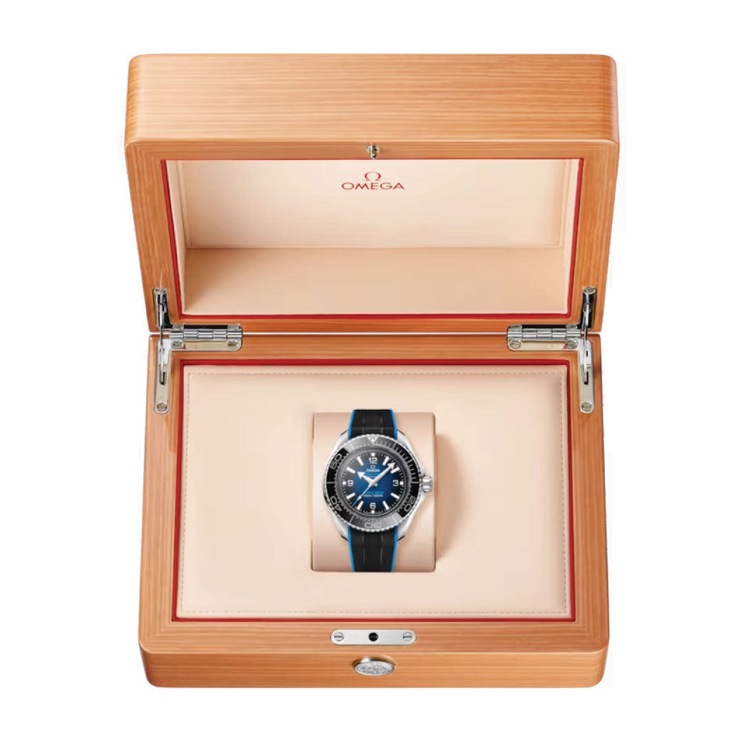 The OMEGA Seamaster Planet Ocean 6000M Ultra Deep Co-Axial Master Chronometer 45.5mm Watch in a wooden presentation box showcases a captivating blue and silver design paired with a black strap. The open lid reveals the beige interior, adorned with the iconic OMEGA Seahorse logo, emphasizing this exquisite water-resistant timepiece.