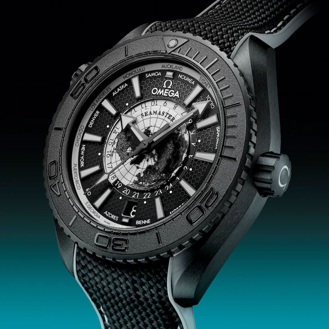 Close-up of the OMEGA Seamaster Planet Ocean 600m Co-Axial Master Chronometer 43.5mm watch, featuring a sleek black ceramic case and strap, set against a gradient black and teal background.