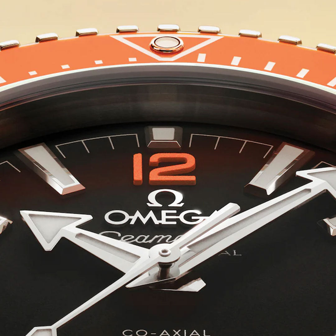 Close-up of the OMEGA Seamaster Planet Ocean 600M Co-Axial Master Chronometer 42mm. This stainless steel dive watch features a black dial, bold white hands, orange “12,” and an orange bezel at the top—classic OMEGA style.