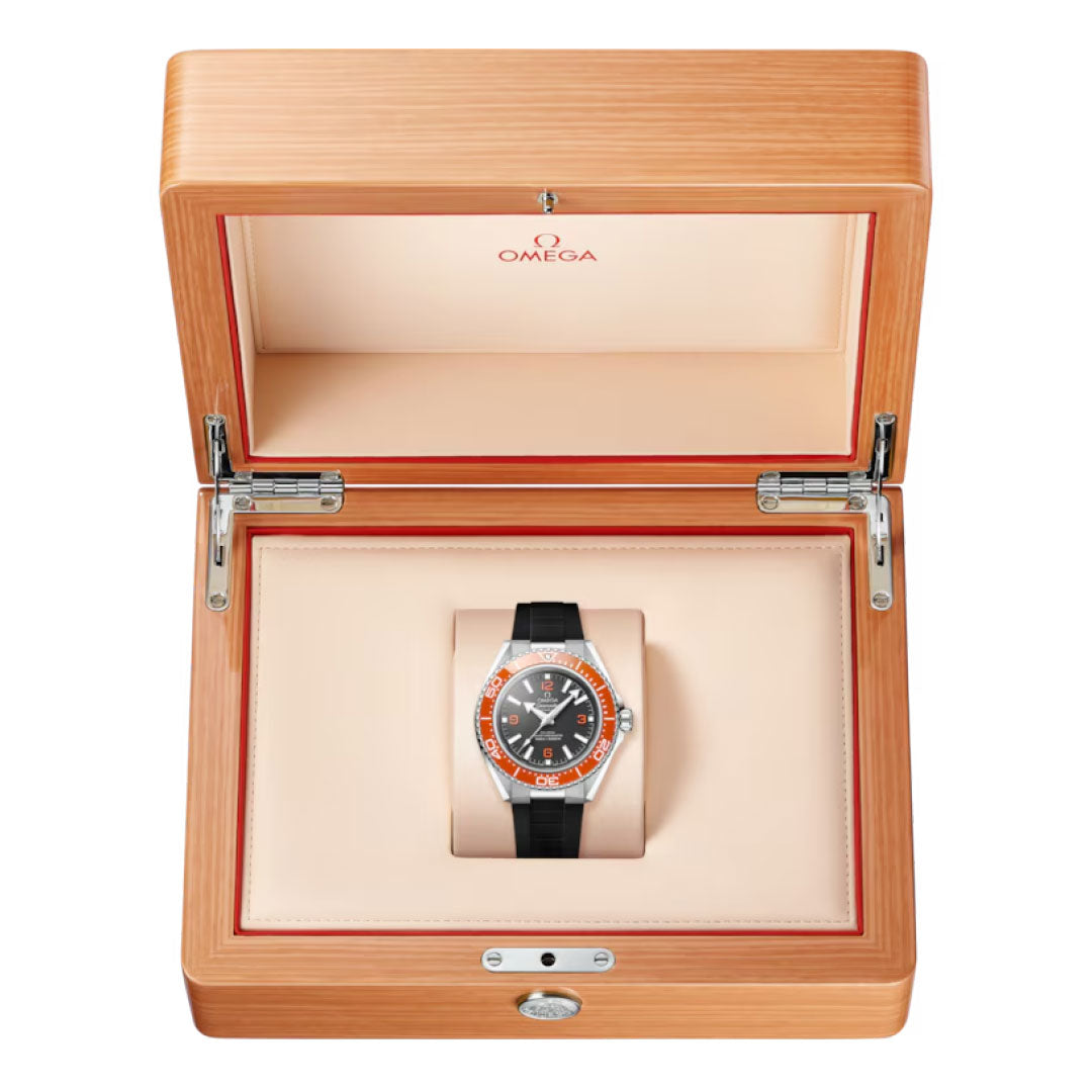 The OMEGA Seamaster Planet Ocean 600M Co-Axial Master Chronometer 42mm Watch with a black strap and orange accents is displayed in an open, light wood OMEGA box with a beige interior.