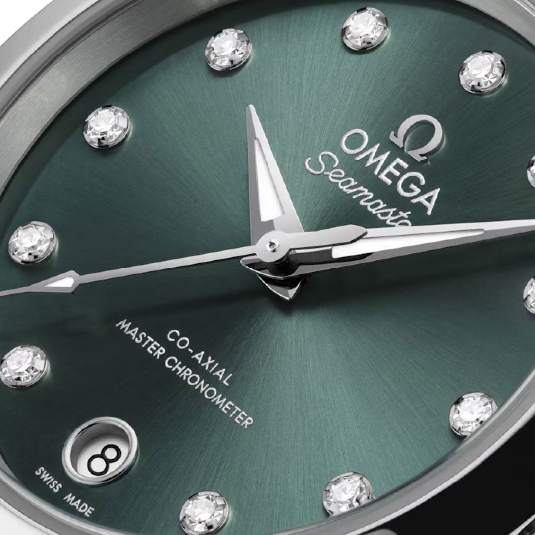 Close-up of the OMEGA Seamaster Aqua Terra 150M Co-Axial Master Chronometer 30mm watch face, featuring a green sunburst dial, diamond hour markers, date window at 6 o’clock, silver hands, and visible OMEGA branding.