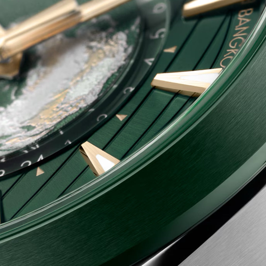 Close-up of the OMEGA Seamaster Aqua Terra 150M Worldtimer Co-Axial Master Chronometer 43mm watch, with a green face, gold triangular hour markers, and textured central design. The word "Bangkok" is partially visible on the stainless steel rim, exuding global elegance and OMEGA sophistication.