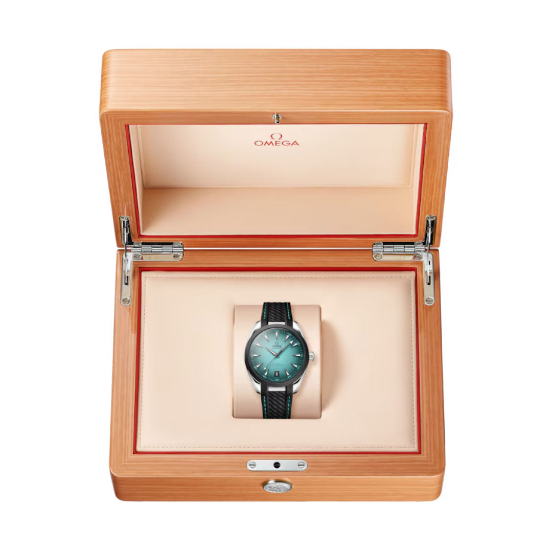 An OMEGA Seamaster Aqua Terra 150M Co-Axial Master Chronometer 41mm Watch with a teal dial and black strap is displayed in an open wooden box with a cream interior and red trim, viewed from above.