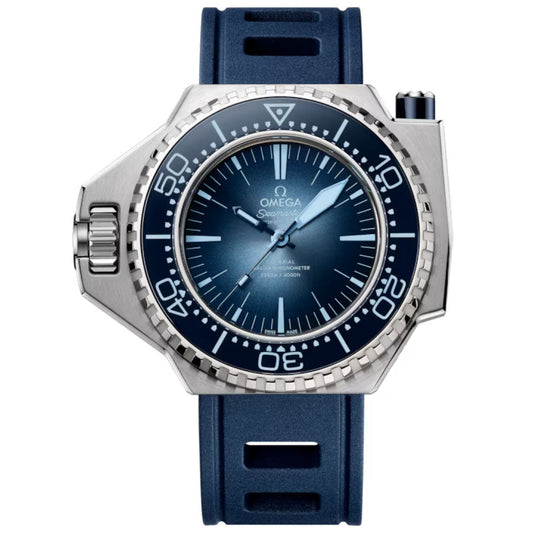 A close-up of the OMEGA Seamaster Ploprof 1200M Co-Axial Master Chronometer 55mm x 45mm watch, featuring a blue gradient dial, white markers, silver bezel, blue rubber strap, and a robust case with a prominent right-side crown guard.