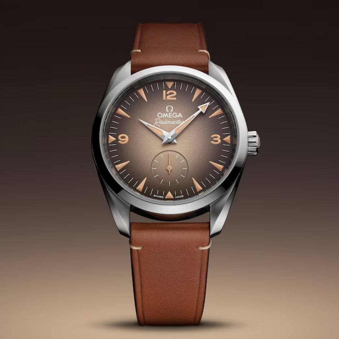 The OMEGA Seamaster Railmaster Co-Axial Master Chronometer 38mm Watch features a gradient brown dial with Arabic numerals, a brown leather strap, and is showcased against a matching brown background.