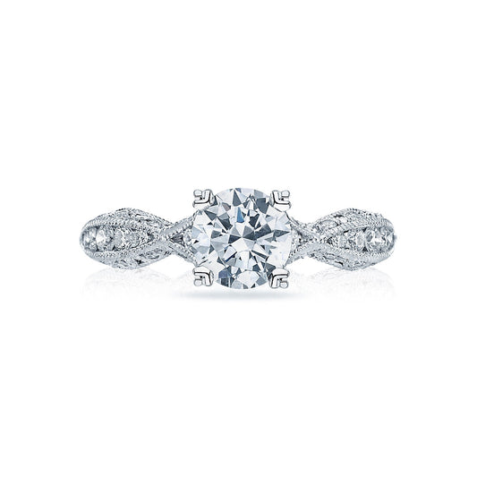 Experience the charm of Tacori with the Classic Crescent 18K White Gold Round Brilliant Semi Mount Solitaire Engagement Ring. This exquisite piece features a round diamond centerpiece securely set in four prongs, complemented by a band adorned with intricate detailing and smaller diamonds in a twisting pattern. Perfect for those pursuing timeless elegance in an engagement ring.