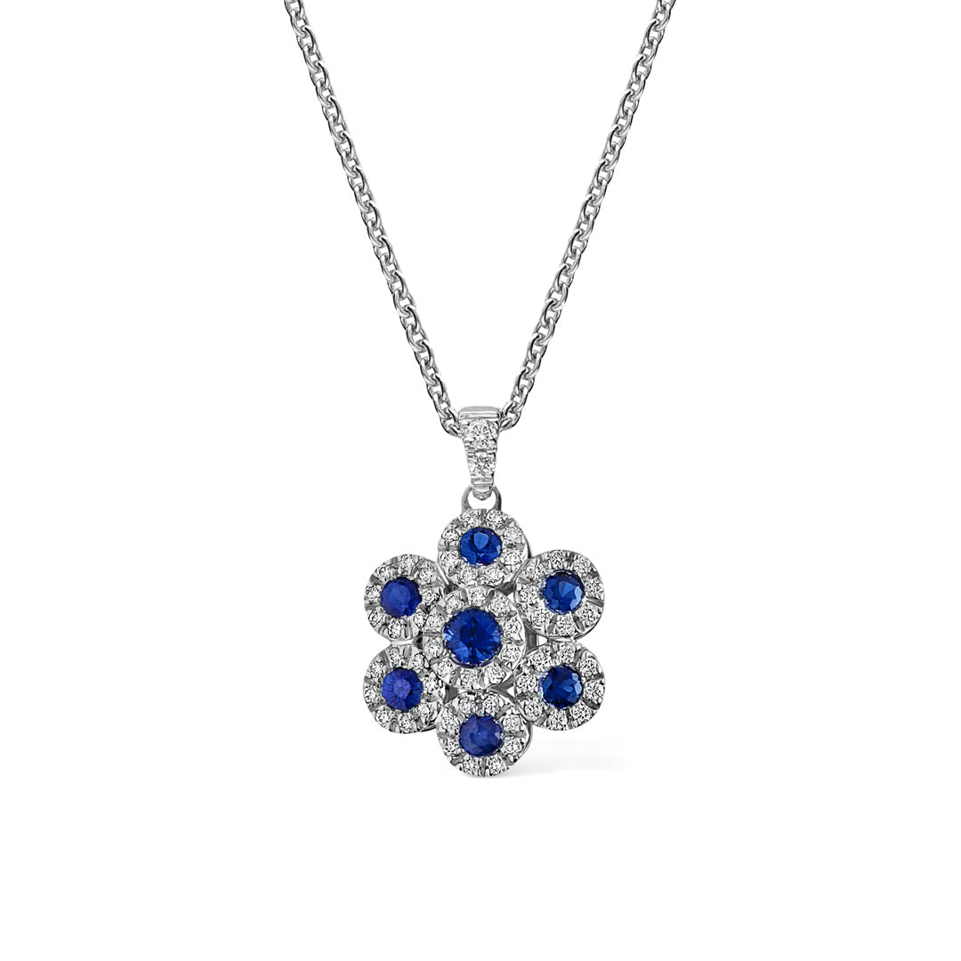 The Leo Pizzo Augusta Collection necklace is an 18K white gold piece, showcasing Italian craftsmanship with a floral pendant adorned with natural blue sapphires and bordered by small white diamonds, elegantly hanging from a closely linked chain.