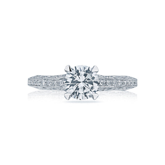 The Tacori Classic Crescent 18K White Gold Engagement Ring prominently features a round, brilliant-cut diamond centerpiece, crafted by expert gemologists at Tacori. The ring is set on a meticulously detailed band adorned with small, sparkling stones that enhance its elegance and shine.