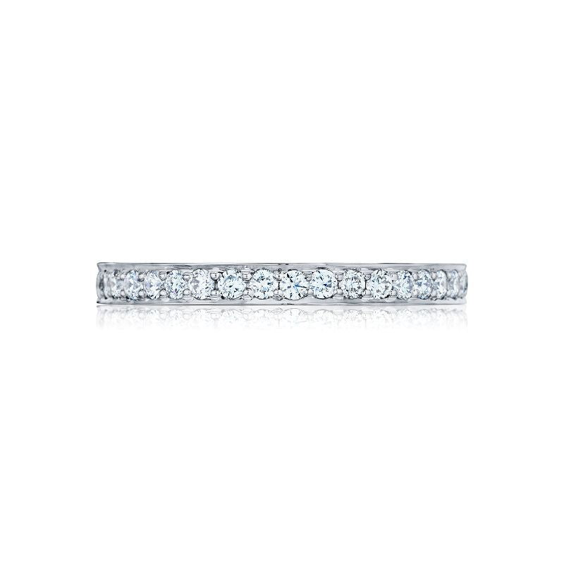 Displayed against a white background is the Tacori Dantela Platinum Round Brilliant Diamond Anniversary Ring, a slim and elegant silver band adorned with small, sparkling diamonds that showcase its classic design.