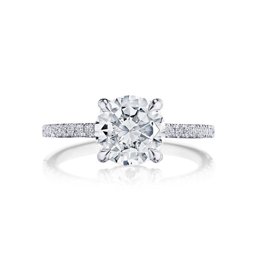 A Tacori Simply 18K White Gold Round Brilliant Semi Mount Engagement Ring is displayed, featuring a large round-cut diamond centerpiece. The band, expertly crafted by Tacori gemologists, includes pavé-set diamonds and a hidden halo to enhance its sparkle. Set against a plain white background, this ring emphasizes its timeless elegance among engagement rings.
