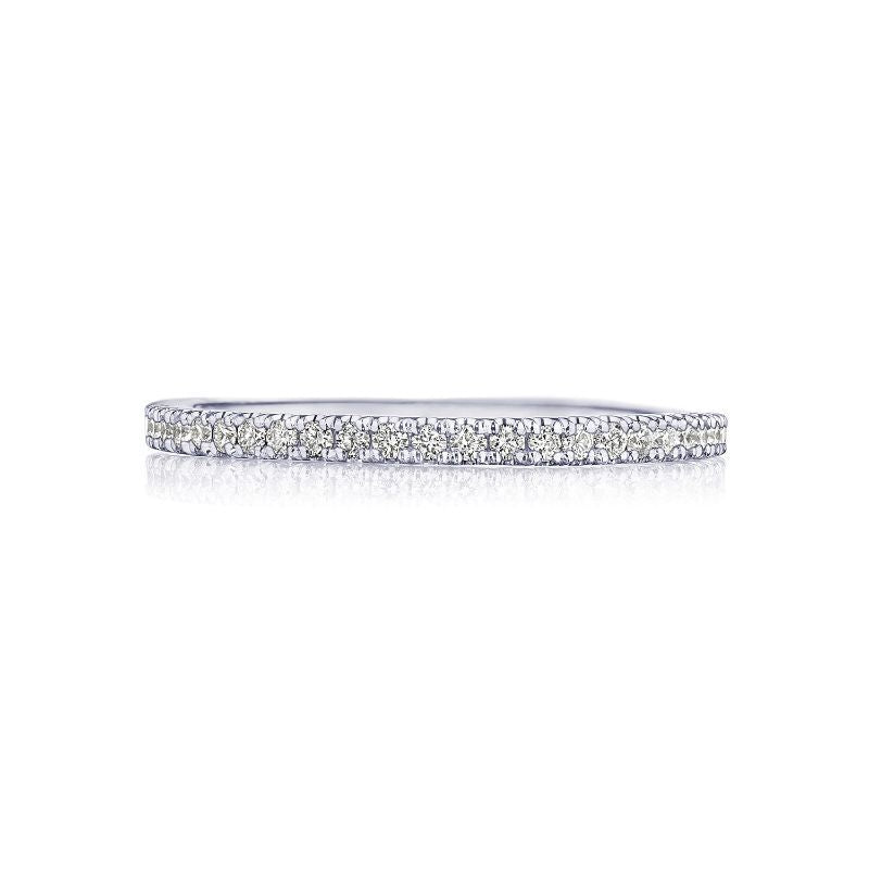 A sleek Tacori Simply 18K White Gold Round Brilliant French Pavé Diamond Eternity Ring glistens on a reflective white surface, capturing the sophistication of engagement rings.