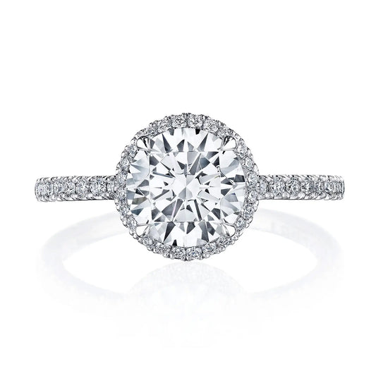 Experience the sophistication of the Tacori Simply Tacori engagement ring, featuring an 18K white gold band. At its heart is a stunning round brilliant diamond with VS clarity, elegantly encircled by a halo of smaller diamonds and further enhanced with a diamond-encrusted band.