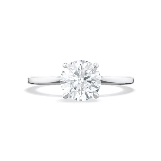 A Tacori Simply 18K White Gold engagement ring showcases a round, brilliant-cut solitaire diamond set on a sleek band with diamond accents, embodying the timeless elegance of TACORI gemologists.