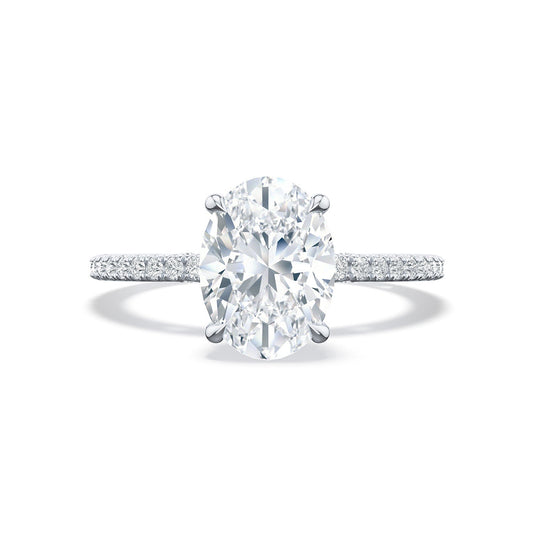 The Tacori Simply 18K White Gold Oval Semi Mount with Diamond Band and Hidden Halo Engagement Ring by Tacori exudes elegance. With a large oval-cut diamond flanked by small pavé diamonds, it perfectly captures bridal details. Presented against a plain white background, its stunning design is highlighted beautifully.