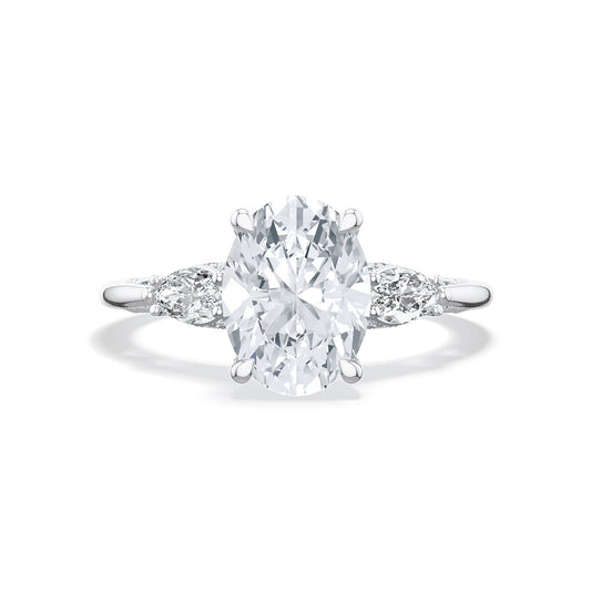 The Tacori Simply 18K White Gold Oval Semi Mount Three Stone Engagement Ring, featuring an oval-shaped diamond centerpiece and two smaller round diamonds on each side, set against a white gold backdrop, showcases the exquisite craftsmanship of Tacori gemologists.
