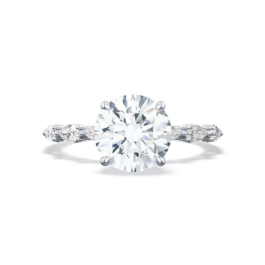 A close-up of the Tacori Sculpted Crescent 18K White Gold Round Brilliant Solitaire Semi Mount Engagement Ring with Diamond Band highlights a central round diamond in a prong setting. The delicate band, featuring smaller marquise-shaped diamonds, dazzles brilliantly against a plain white background.