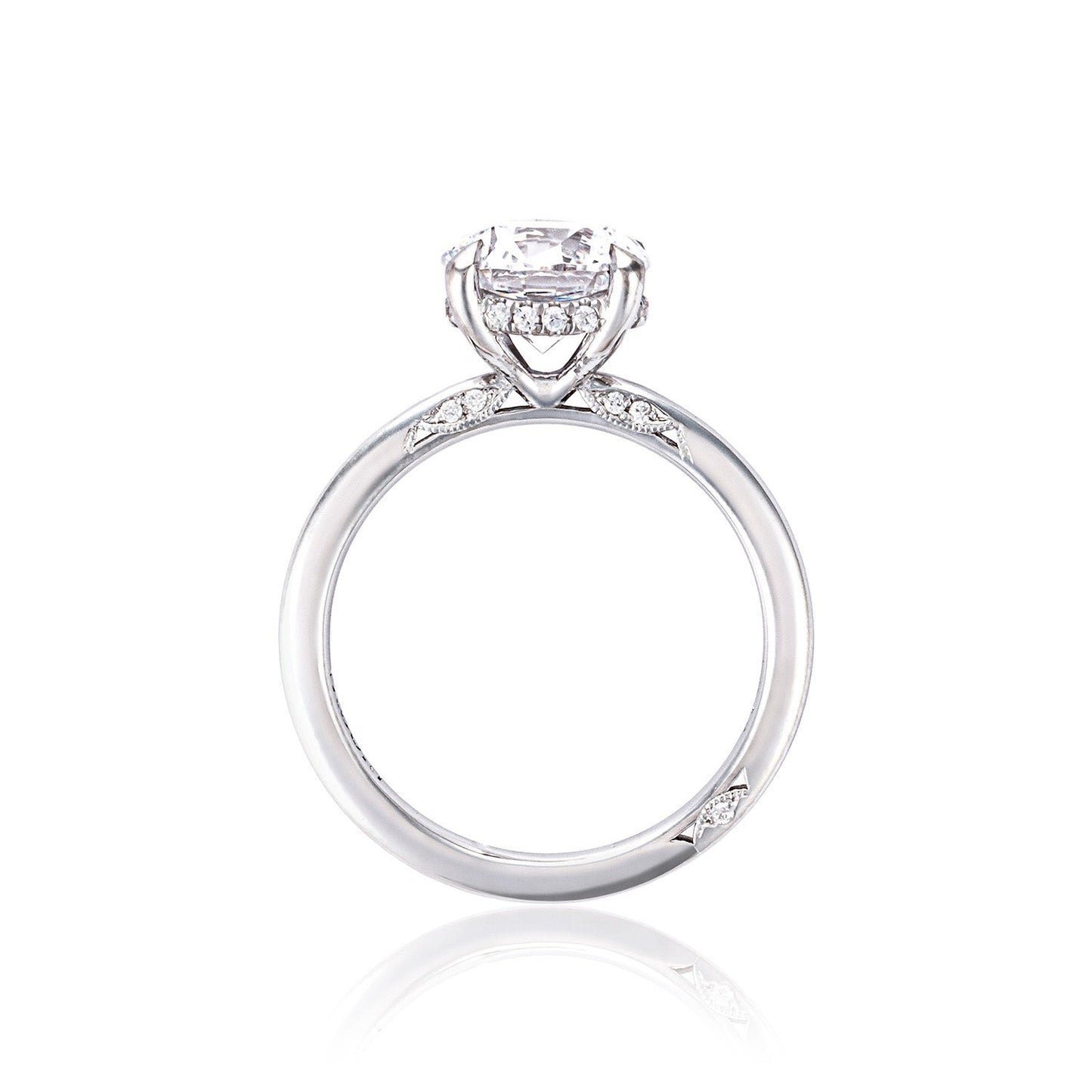 The Tacori Simply 18K white gold engagement ring features a prominent round brilliant solitaire diamond at the center. Its band is accented with smaller diamonds on the sides, presenting an elegant and classic design that emphasizes the timeless allure of diamonds in engagement rings.