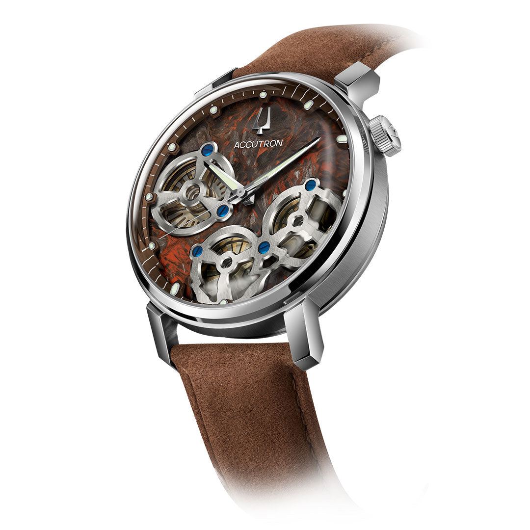The Accutron Spaceview Evolution Electrostatic 43.5mm Watch features a brown suede strap, silver case, and exposed dial with visible gears, set against a marbled reddish-brown background that highlights its electrostatic movement.