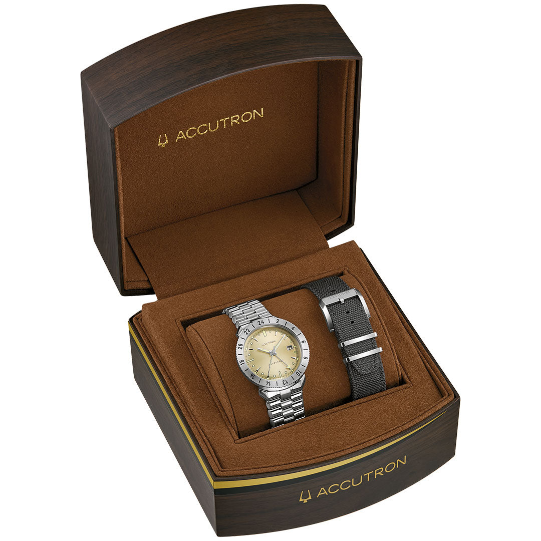 The Accutron Astronaut LTi Automatic 41mm Watch features a silver titanium case, beige dial, and comes in a brown cushioned box with gold Accutron logos and trim, plus an extra black fabric strap. Elegant, versatile design by Accutron.