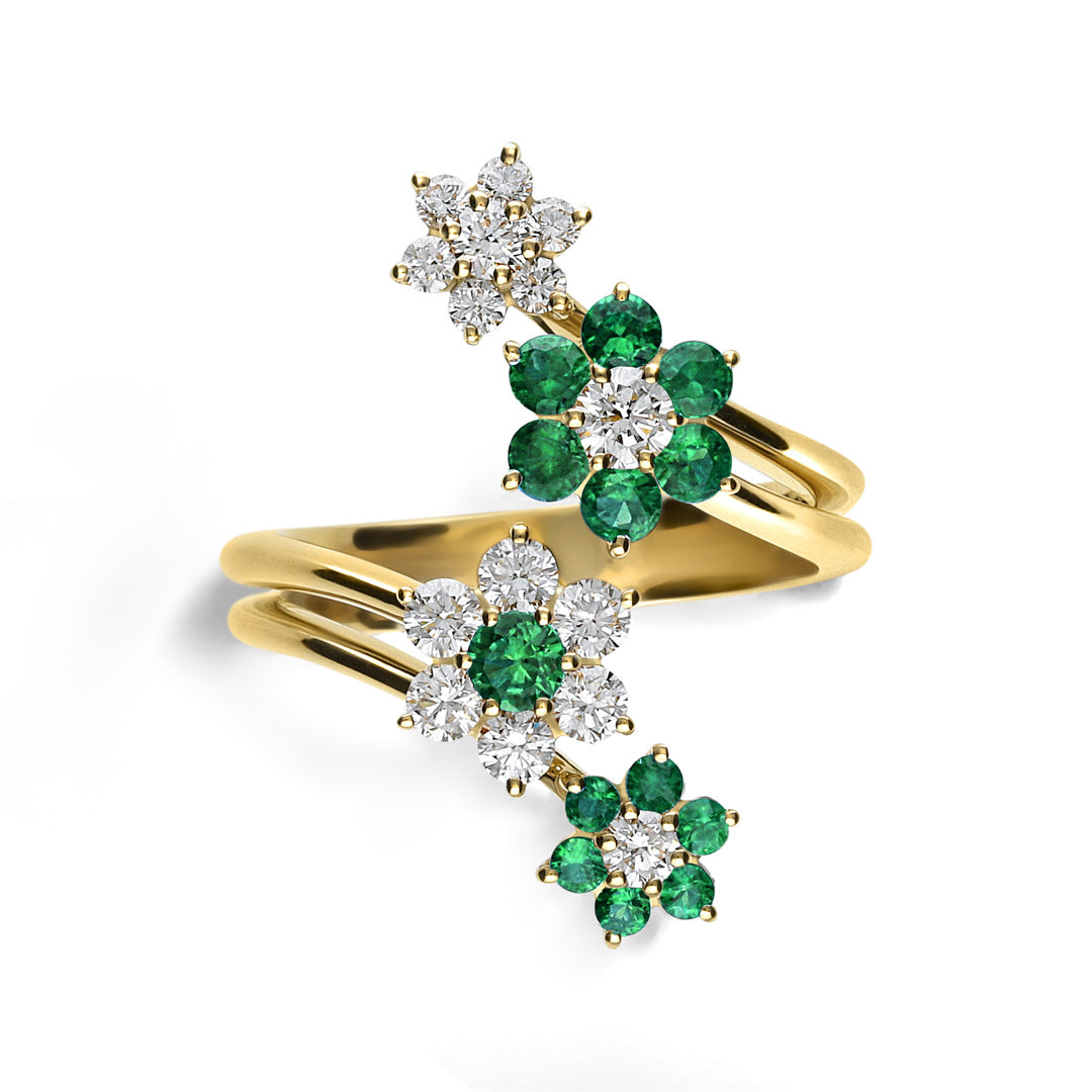 The Leo Pizzo Flora Collection 18K Yellow Gold Diamond Emerald Fashion Ring showcases Italian craftsmanship with a wrap-around design featuring three floral clusters of emeralds and diamonds, spiraling elegantly to create a vibrant contrast against white.
