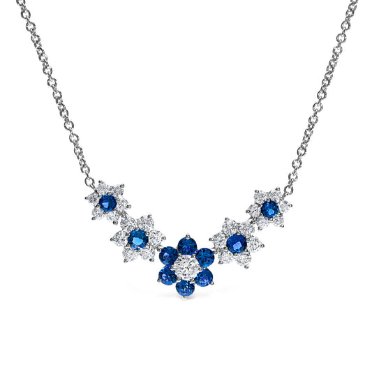 Part of the Leo Pizzo Flora Collection, this 18K white gold necklace displays Italian artistry with a floral motif. It features natural sapphires surrounded by smaller clear stones in a symmetrical design, with the center resembling a flower and additional floral shapes on both sides.