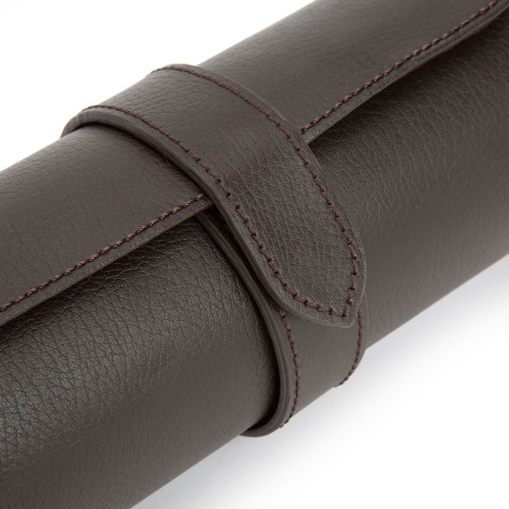A close-up of the WOLF 1834 Blake Triple Watch Roll Brown by WOLF showcases its rich dark brown leather, strap closure, and detailed stitching, set against a white background. This handcrafted watch roll exudes quality and sophistication.