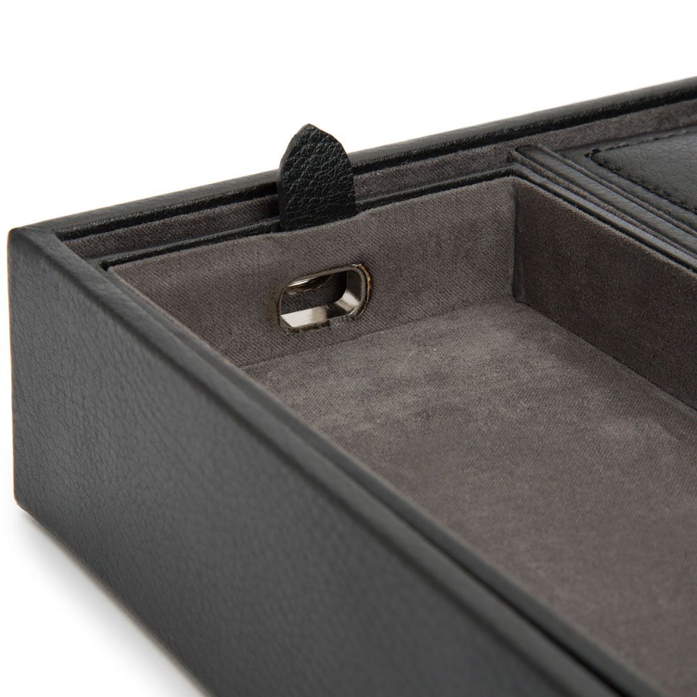 A close-up of the WOLF Blake Valet Jewellery and Watch Tray With Cuff by WOLF, crafted in black leather with a grey suede interior and a corner slot for charging cables—ideal for organizing jewellery or watches.