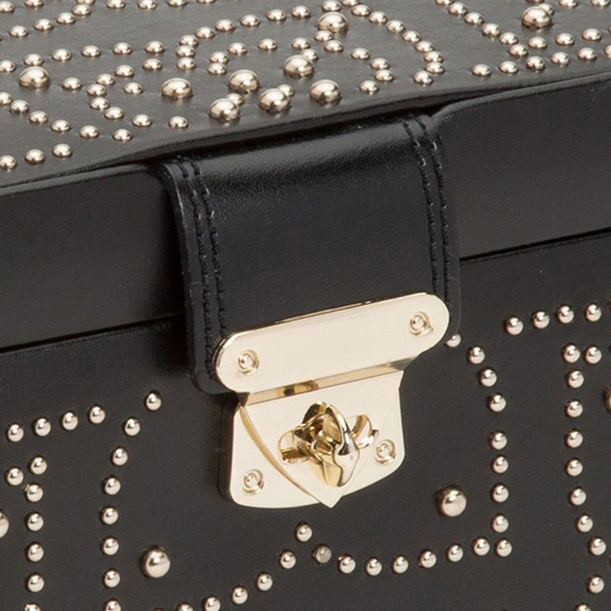 Close-up of the WOLF 1834 Marrakesh Black Jewellery Box, crafted from luxurious leather and embellished with intricate gold studs in swirling patterns. The shiny gold hardware adds a touch reminiscent of Moroccan design, featuring a sleek clasp that enhances the elegance and style synonymous with LusterLoc™ quality.