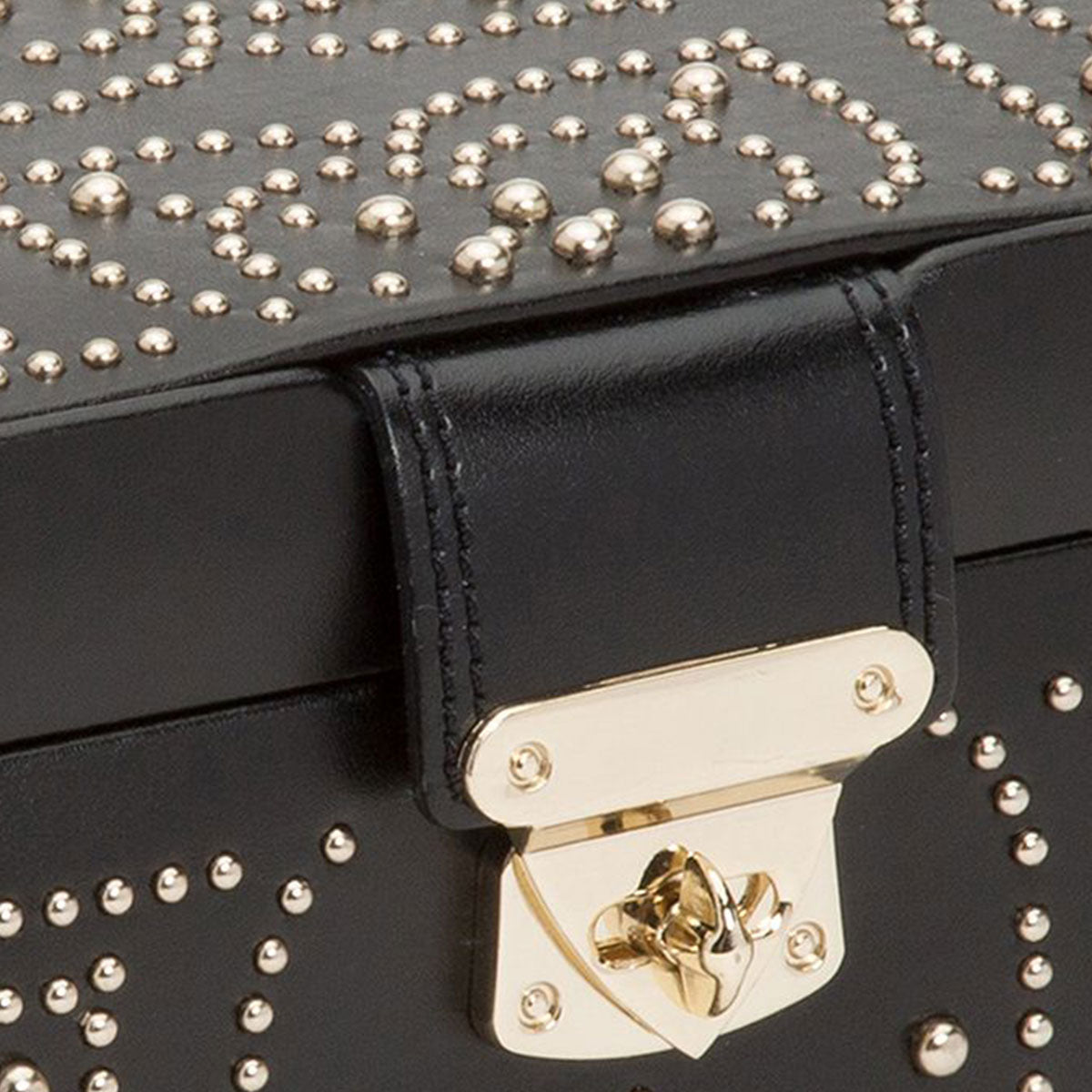 Close-up of a WOLF 1834 Marrakesh Flat Jewellery Box in black leather, embellished with gold studding that forms a decorative pattern. The box features a gold lock clasp on a leather strap, resembling an exquisite leather handbag.