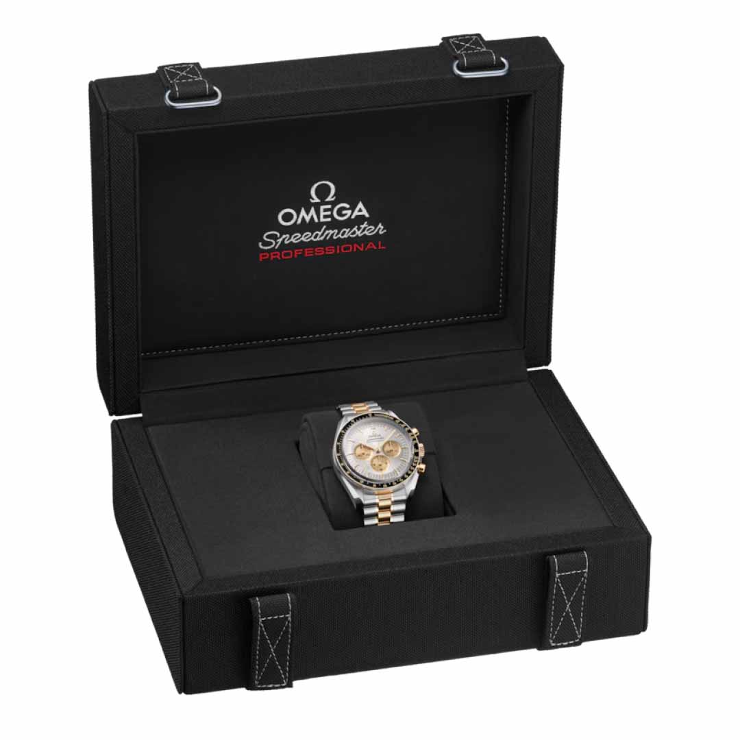 An elegant wristwatch featuring a silver and gold design is presented in an open black box. Inside the lid, the box displays the OMEGA Speedmaster Moonwatch Professional Co-Axial Master Chronometer Chronograph 42mm Watch logo, emphasizing its distinguished chronograph precision.