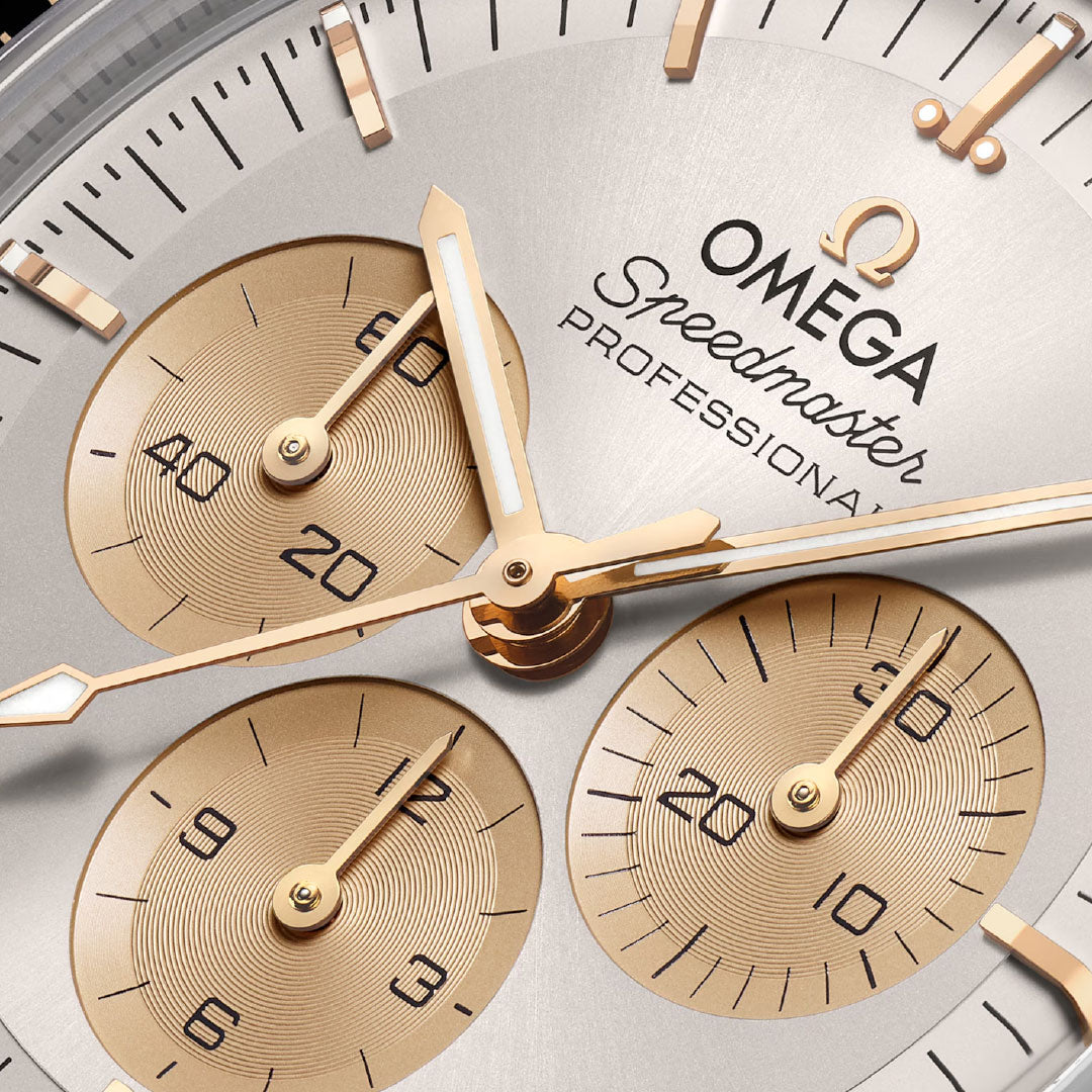 Close-up of the OMEGA Speedmaster Moonwatch Professional Co-Axial Master Chronometer Chronograph 42mm Watch face, displaying three gold subdials, gold hands and hour markers on silver, with "OMEGA Speedmaster Professional" text.