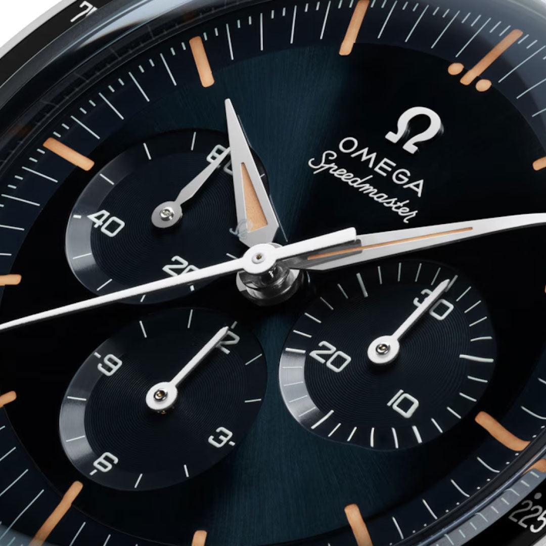 Close-up of the OMEGA Speedmaster First OMEGA in Space Co-Axial Master Chronometer 39.7mm, showing its iconic tachymeter scale, three subdials, white hands, gold markers on a dark dial, and prominent OMEGA logo and Speedmaster name.
