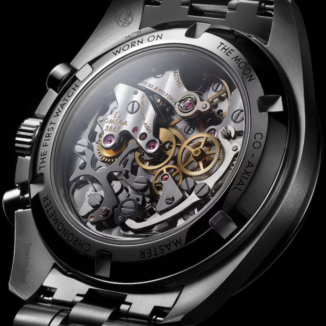 Close-up of the OMEGA Speedmaster Moonwatch Professional Co-Axial Master Chronometer Chronograph 42mm’s transparent caseback reveals its intricate movement and engraved text: "The First Watch Worn on the Moon.