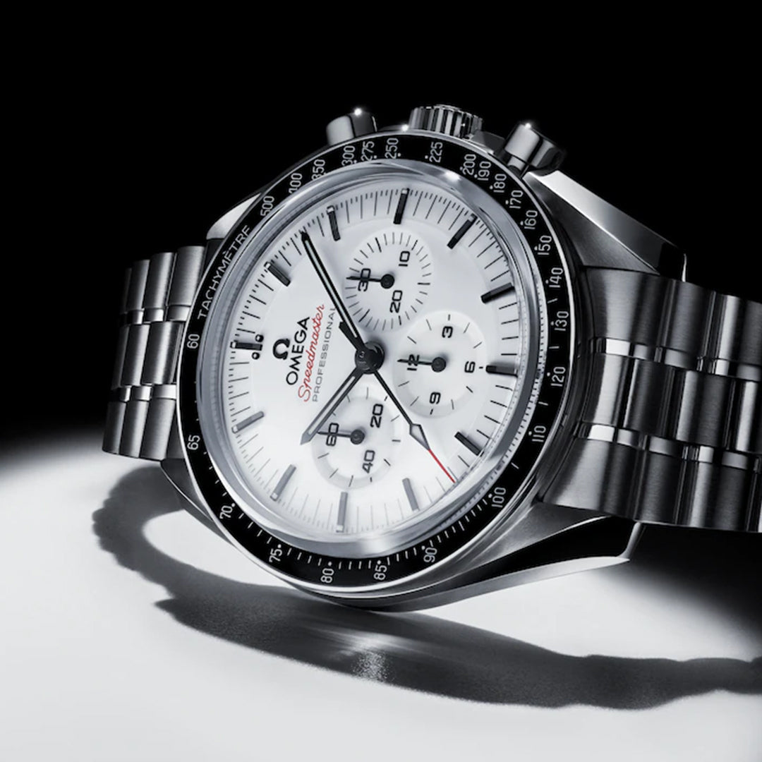 A close-up of the OMEGA Speedmaster Moonwatch Professional Co-Axial Master Chronometer Chronograph 42mm Watch, featuring a white dial, black markers, and stainless steel bracelet, displayed with dramatic lighting to highlight its chronograph.