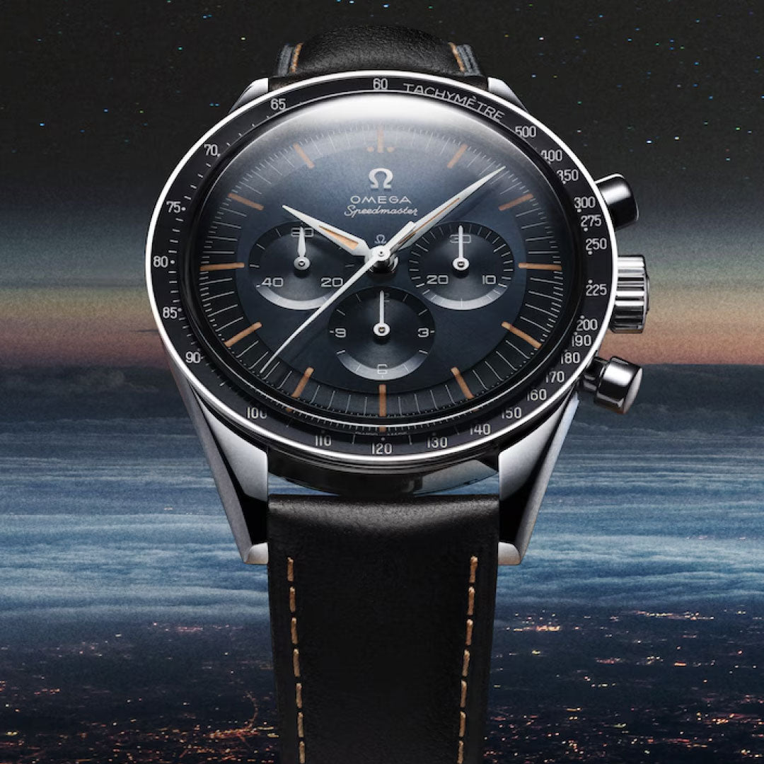 A close-up of the OMEGA Speedmaster First OMEGA in Space Co-Axial Master Chronometer 39.7mm Watch with a black dial, three subdials, and black leather strap, set against Earth’s atmosphere transitioning from night to dawn.