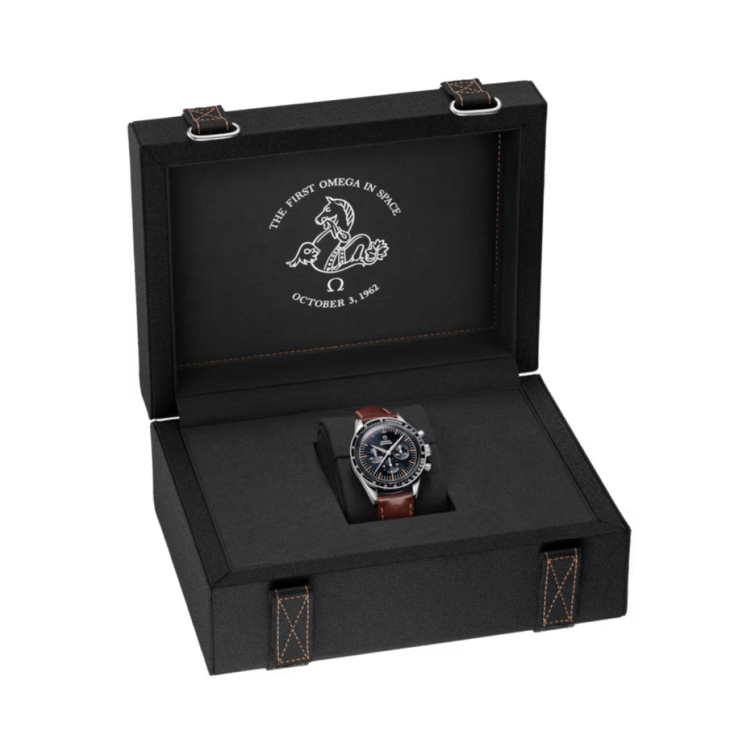 The OMEGA Speedmaster First OMEGA in Space Co-Axial Master Chronometer 39.7mm Watch with a brown leather strap is shown in an open black box, whose lid features white text: "The first Omega in space, October 3, 1962.