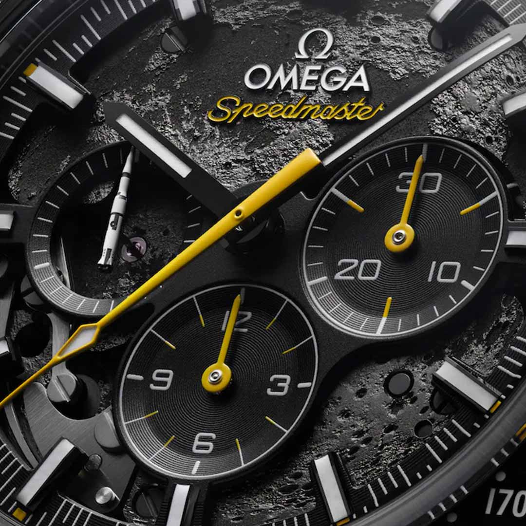 Close-up of the OMEGA Speedmaster Dark Side of the Moon Co-Axial Master Chronometer 44.25mm watch face featuring yellow accents and sleek black ceramic. The image showcases detailed chronograph dials and the Omega logo, highlighting the intricate design and textures that echo its connection to historic moon landings.