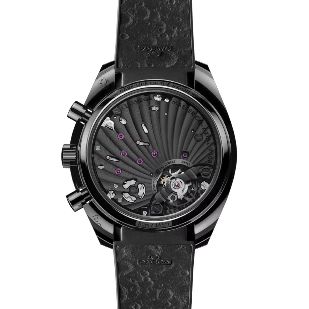 Close-up of the OMEGA Speedmaster Dark Side of the Moon Co-Axial Master Chronometer 44.25mm Watch, showing its transparent case back with visible gears, purple jewels, and Omega logo on a textured strap.