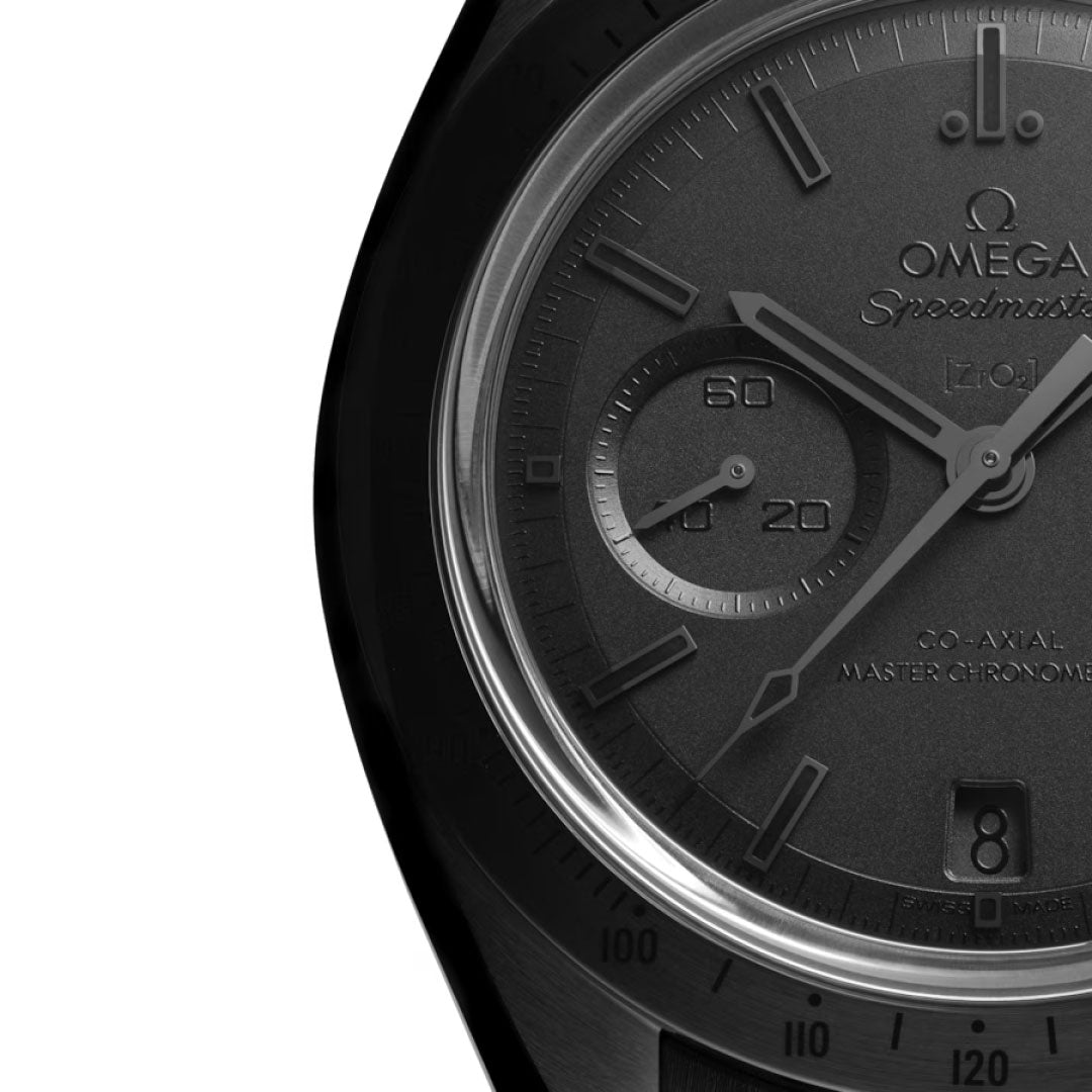 Close-up of the OMEGA Speedmaster Dark Side of the Moon Co-Axial Master Chronometer 44.25mm Watch, displaying its black ceramic dial with subdial, hands, date window, and a section of the case and bezel on the left.