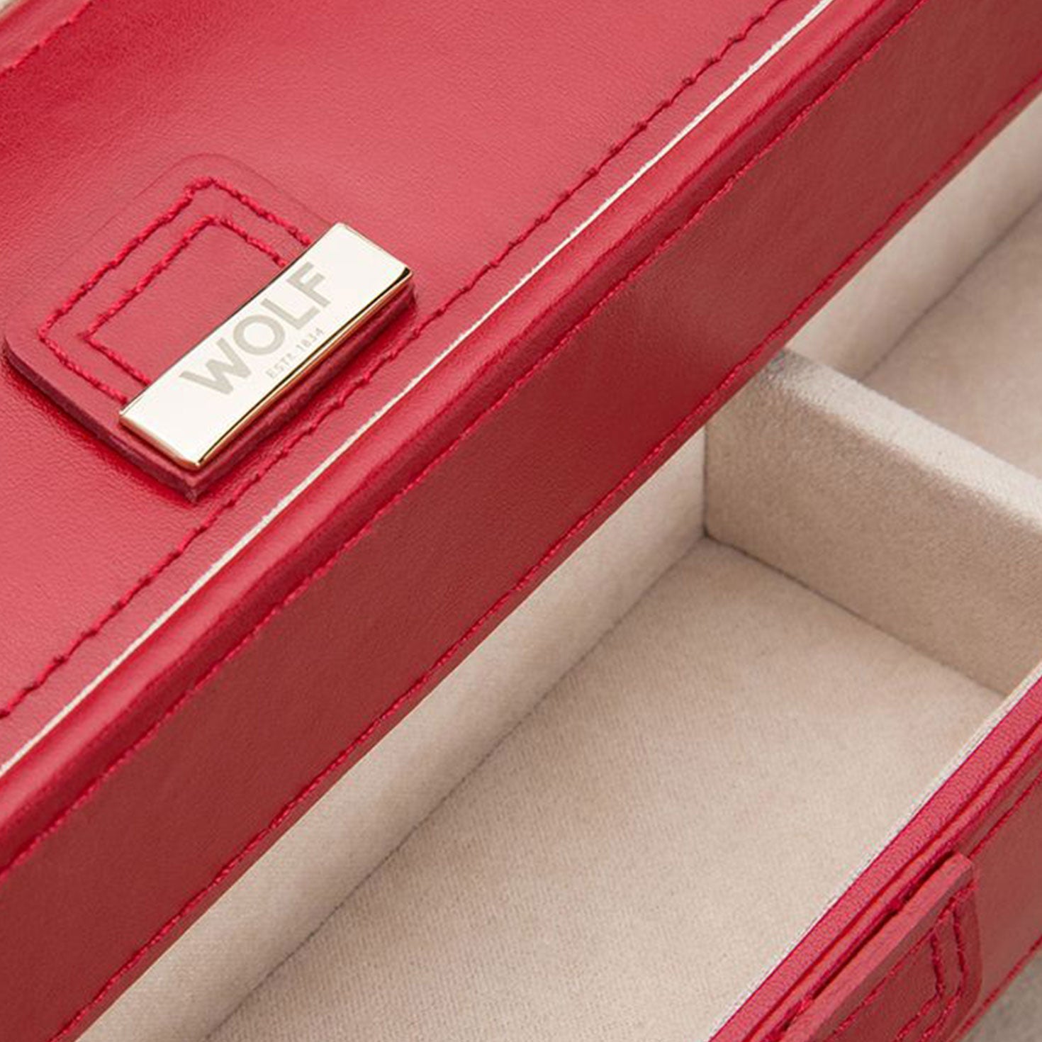 Close-up of an open WOLF 1834 Caroline Red Large Jewellery Box crafted in diamond-quilted red leather with soft beige interior compartments. The lid features a gold-tone plaque with the brand name "WOLF," complemented by advanced LusterLoc™ technology for enhanced protection.