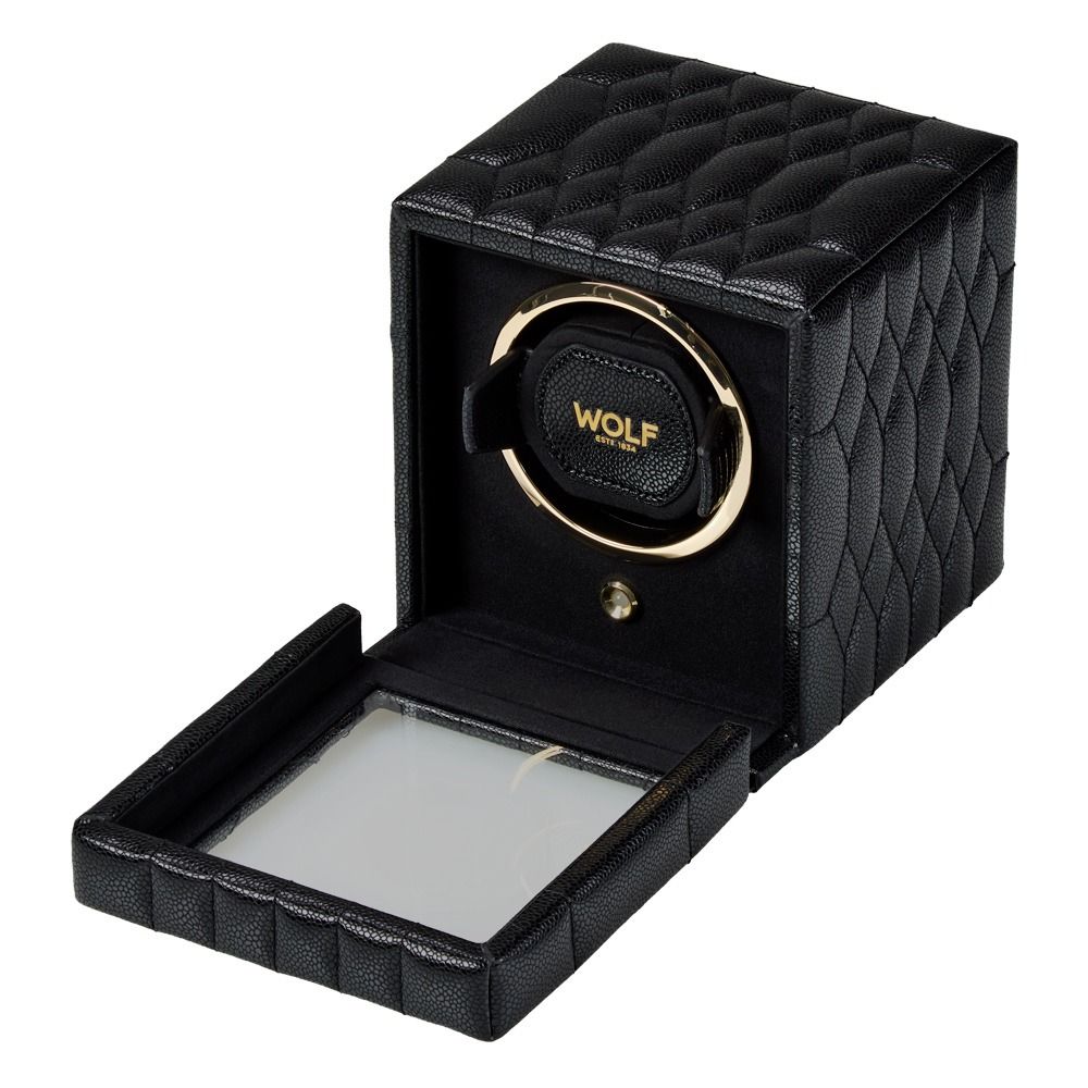 The WOLF 1834 Lauren Single Watch Winder Black, featuring black textured exteriors, gold accents, and chrome-finished hardware, is displayed with its glass door open to showcase the ebony macassar interior crafted to hold and rotate a watch. The “WOLF” brand name is prominently labeled on the box.