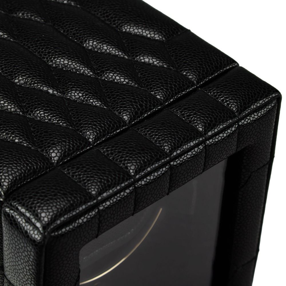 Close-up of the WOLF 1834 Lauren Single Watch Winder in black quilted leather, showcasing its textured design, chrome-finished hardware, and a transparent window on one side that reveals part of the watch inside.