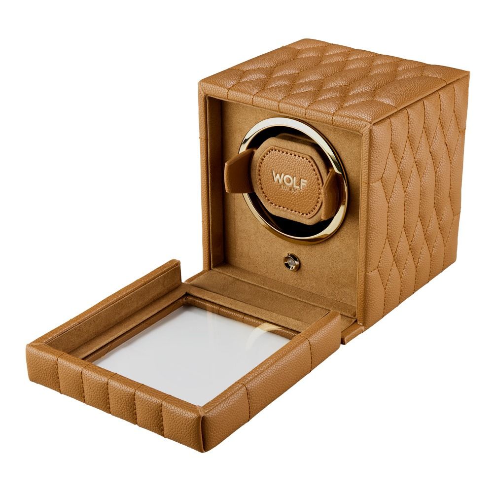 A tan, quilted WOLF 1834 Lauren Single Watch Winder Carmel by WOLF is shown with its glass door open, revealing a circular holder inside adorned with “WOLF” in gold accents. Drawing inspiration from classic British roadster design and finished with refined ebony macassar wood details, this elegant piece reflects both luxury and tradition.