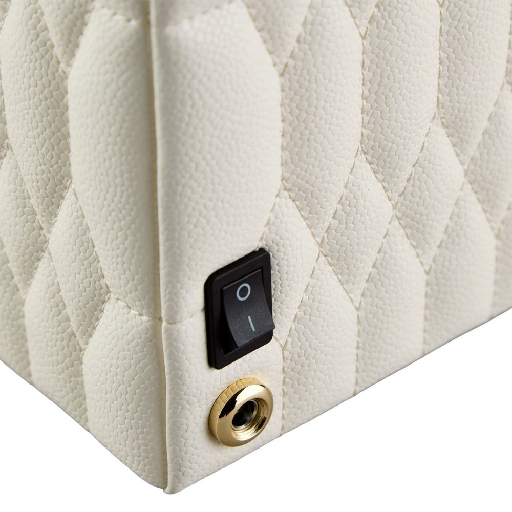 A close-up of the WOLF 1834 Lauren Single Watch Winder in Ivory reveals a cream-colored, textured surface with a quilted pattern, highlighted by chrome hardware including a black power switch labeled “I” and “O” and a metallic audio jack port—details that evoke the refined finish characteristic of luxury timepiece accessories from WOLF.
