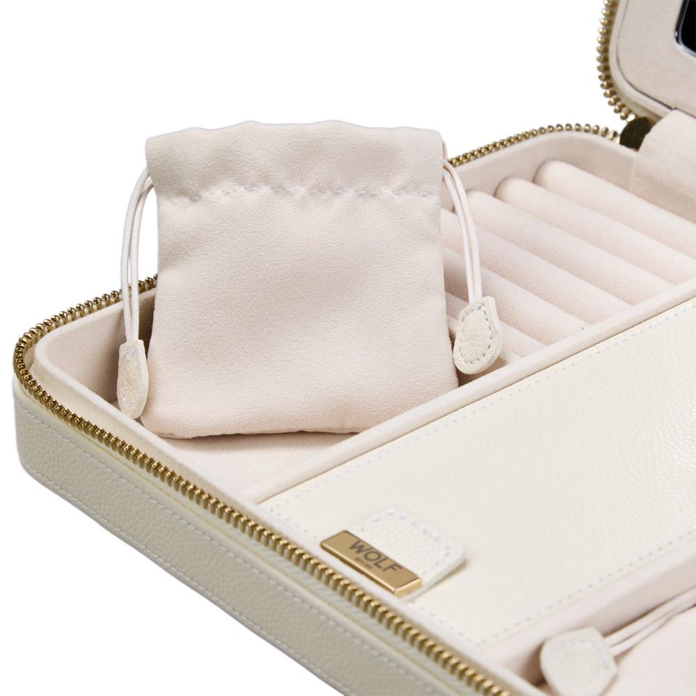 A small drawstring pouch sits inside an open WOLF 1834 Lauren Large Zip Case Ivory, a cream-colored leather jewelry organizer by WOLF featuring a gold zipper and velvet-lined compartments.
