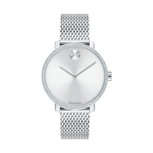 The Movado BOLD Shimmer Quartz 34mm Watch showcases a minimalist design with a mesh metal strap and silver dial. The minimal hour markers are accentuated by the iconic dot at the 12 o'clock position. Its stainless steel case, complemented by a crystal pave bezel, enhances the elegance and sophistication typical of the Movado brand.